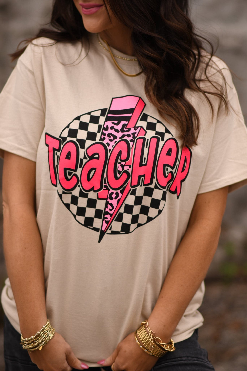 Trendy teacher wearing tan leopard bolt graphic t-shirt styled with jeans and gold accessories