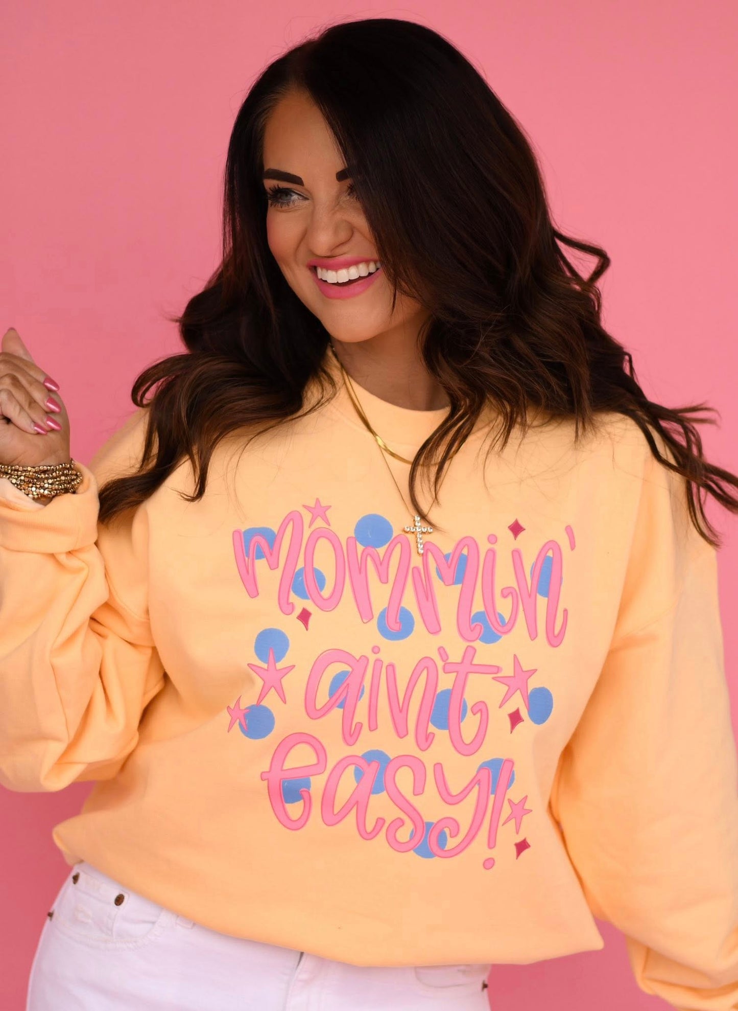 Woman wearing a yellow sweatshirt with text on a pink background