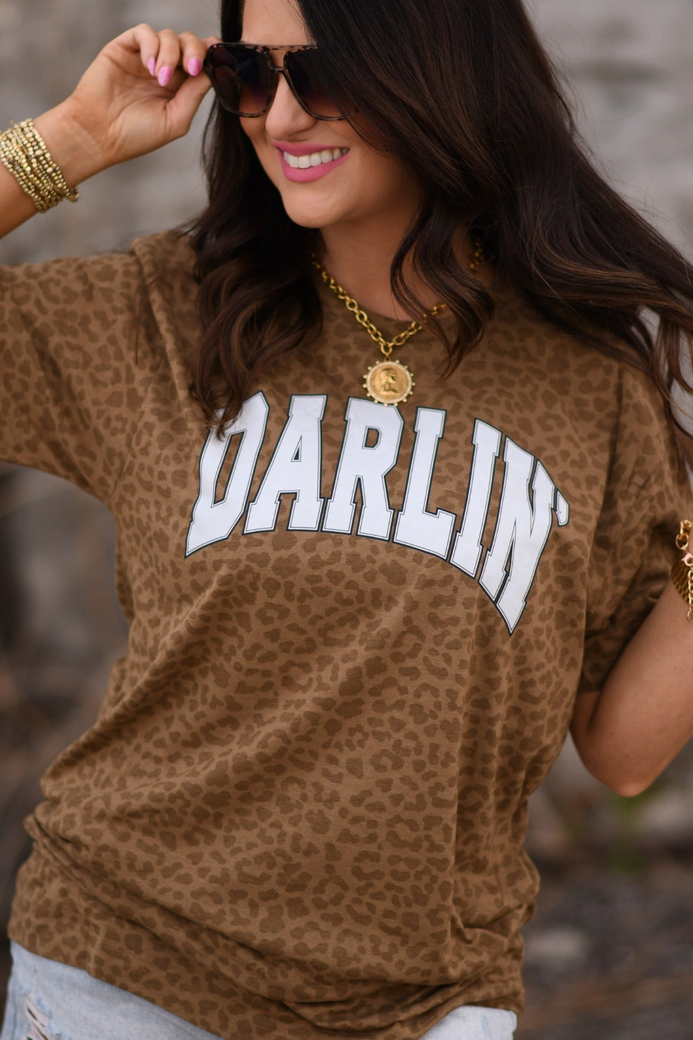 Woman wearing a brown leopard print “Darlin” graphic tee styled with denim shorts and western jewelry