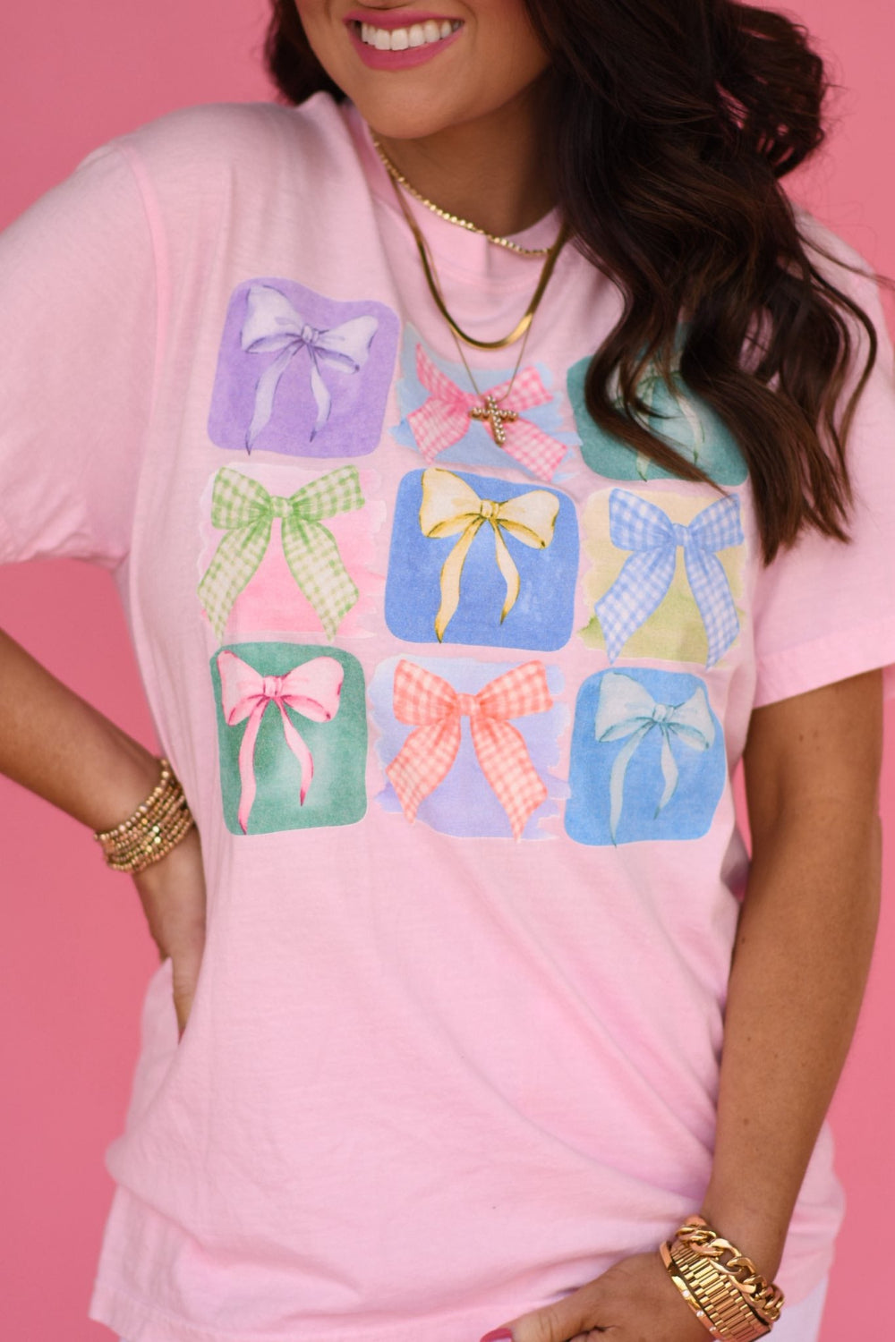 Woman modeling pink Comfort Colors unisex tee featuring nine pastel gingham bow graphics, styled for spring and Easter outfit inspiration