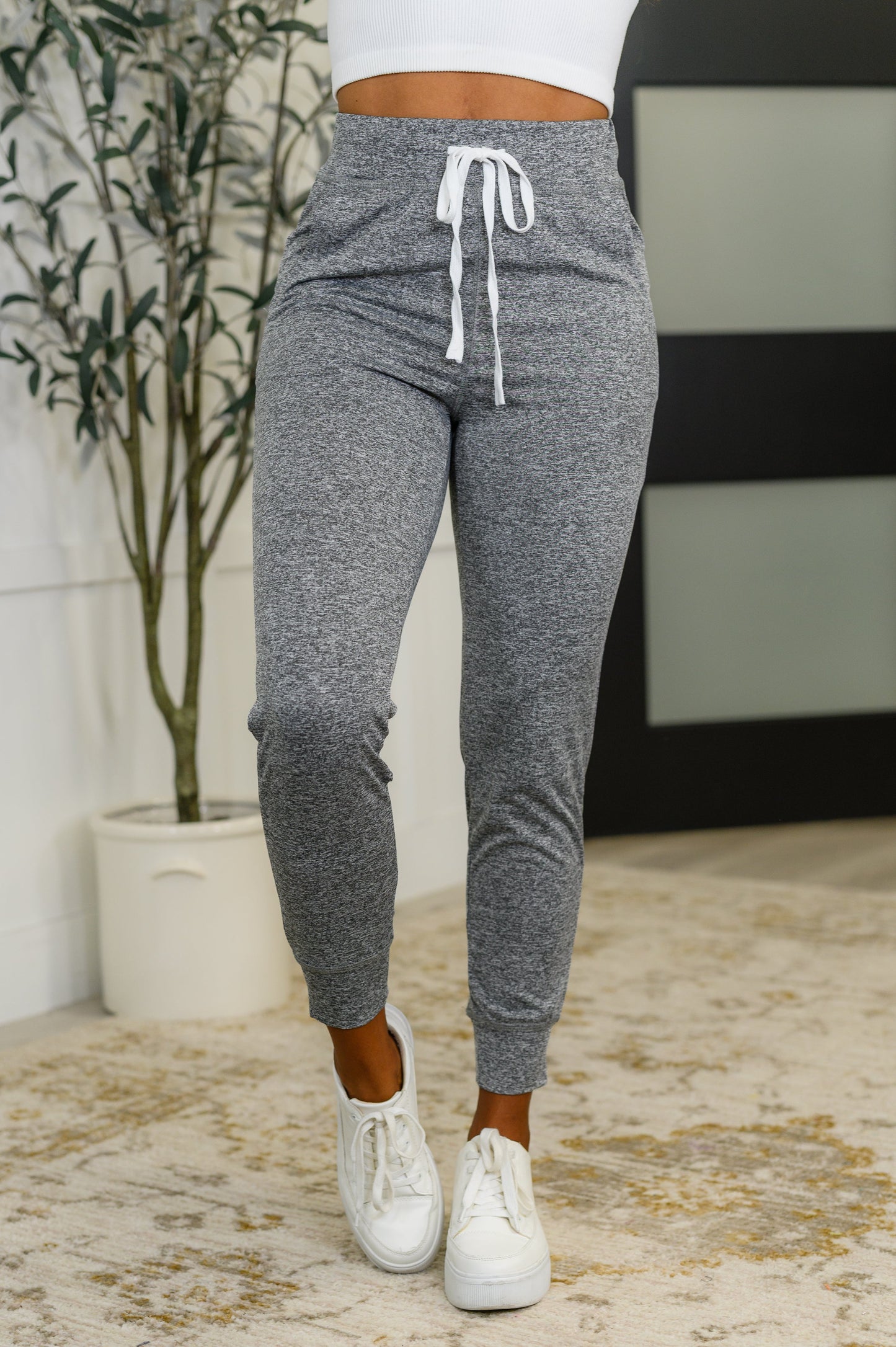 A pair of gray athletic joggers with a cased elastic waistline and drawstring, featuring functional side pockets and a banded hem.