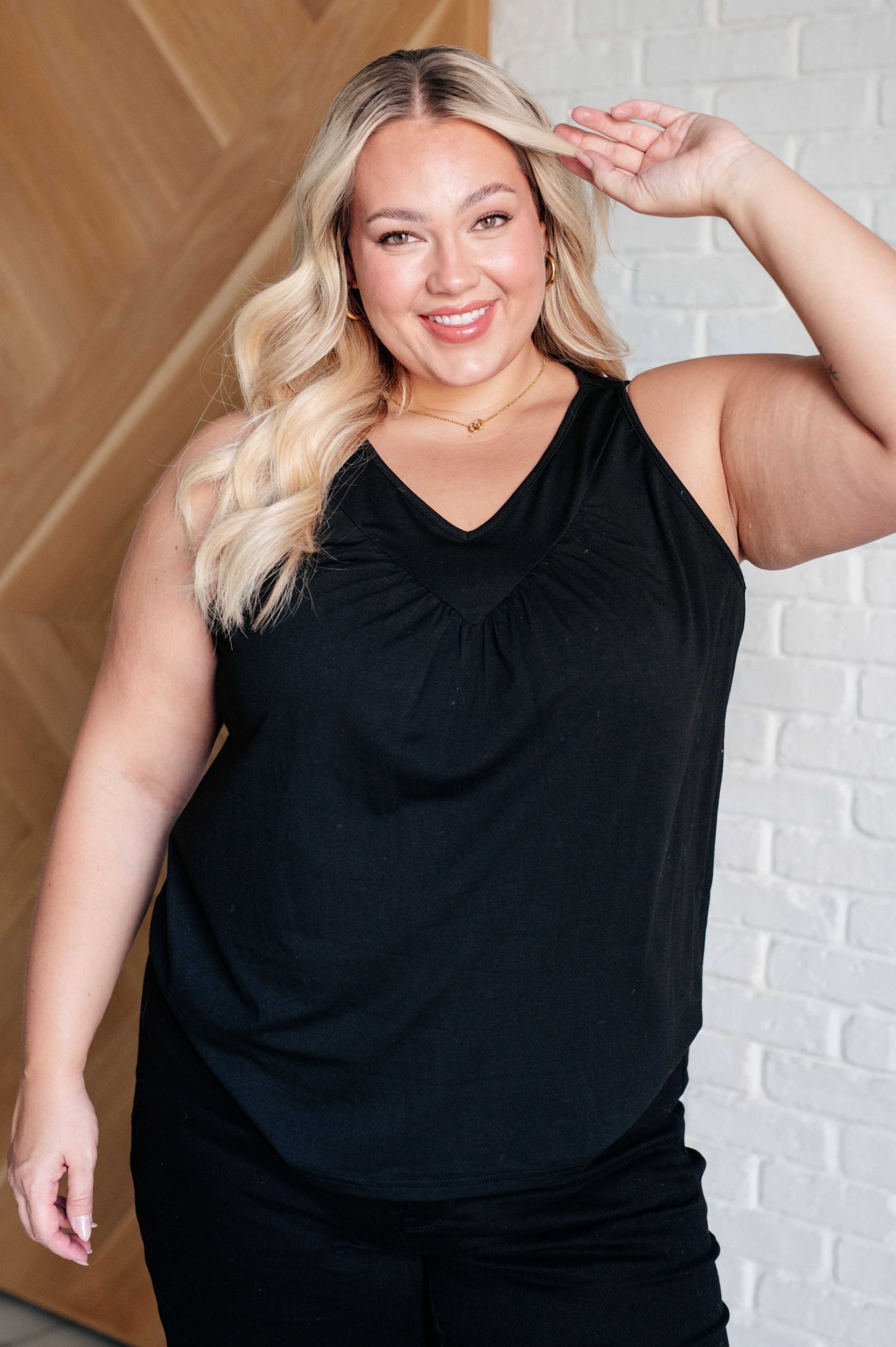black V-neck tank top with ruched detailing, sleeveless design, in a casual setting.