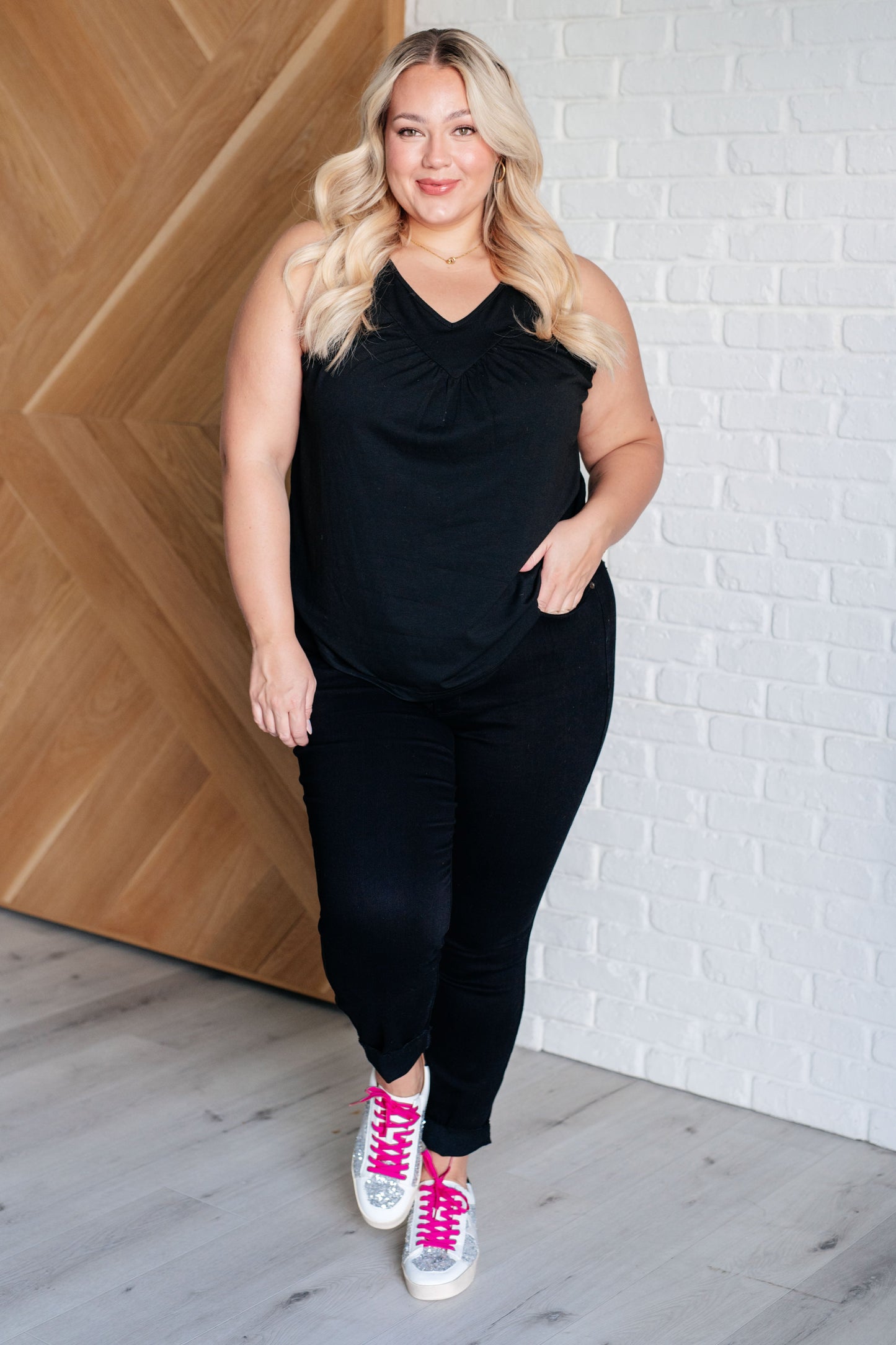 black V-neck tank top with ruched detailing, sleeveless design, in a casual setting.