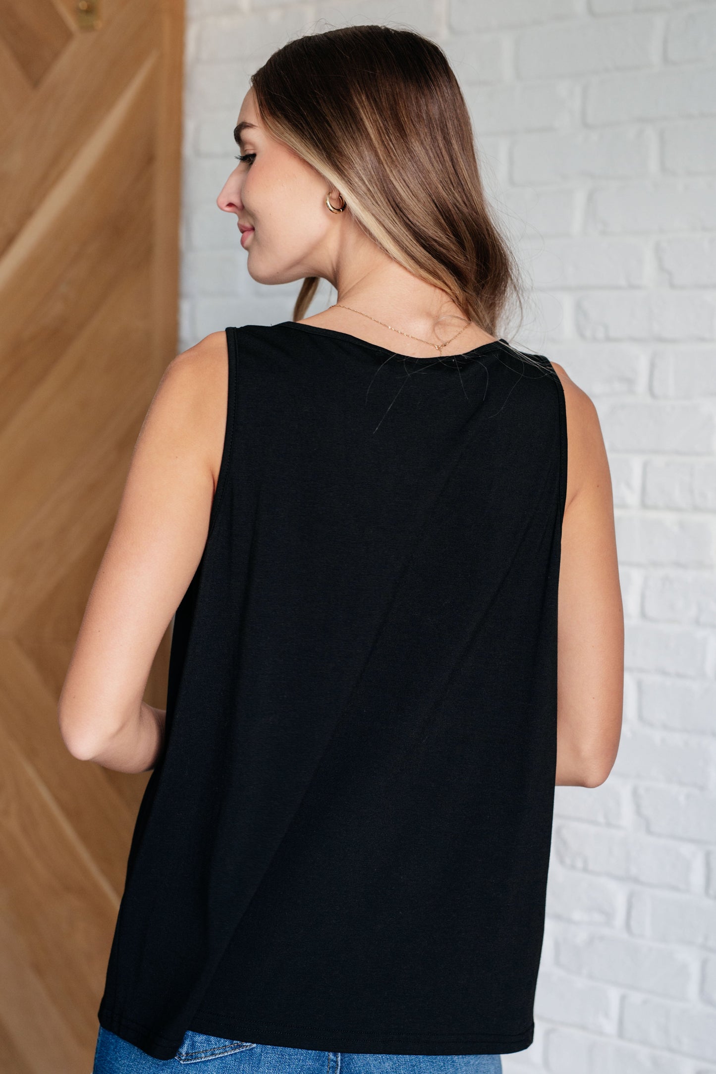 black V-neck tank top with ruched detailing, sleeveless design, in a casual setting.