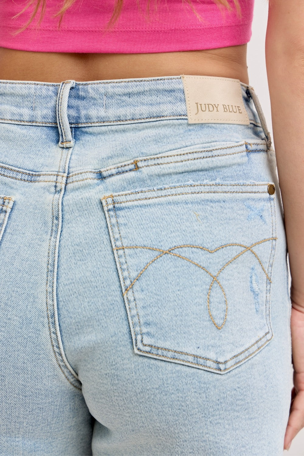 High waisted light wash distressed denim dad shorts with raw hem and relaxed fit front and back view on model outdoors