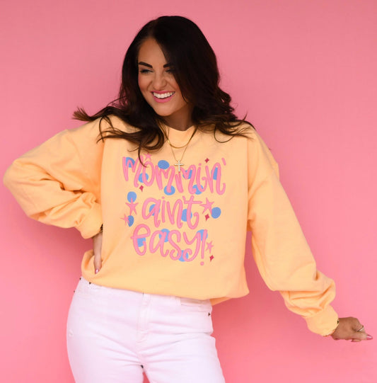 Woman wearing a yellow sweatshirt with colorful text on a pink background