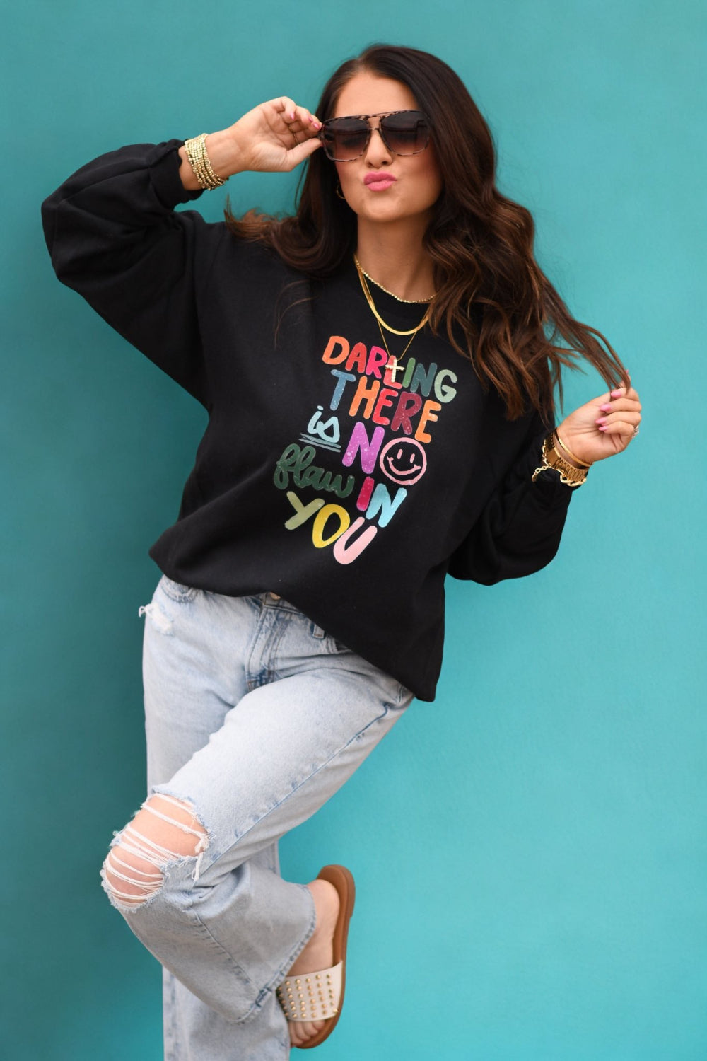 Woman wearing black sweatshirt with colorful text that reads Darling There Is No Flaw In You, positive affirmation graphic sweatshirt