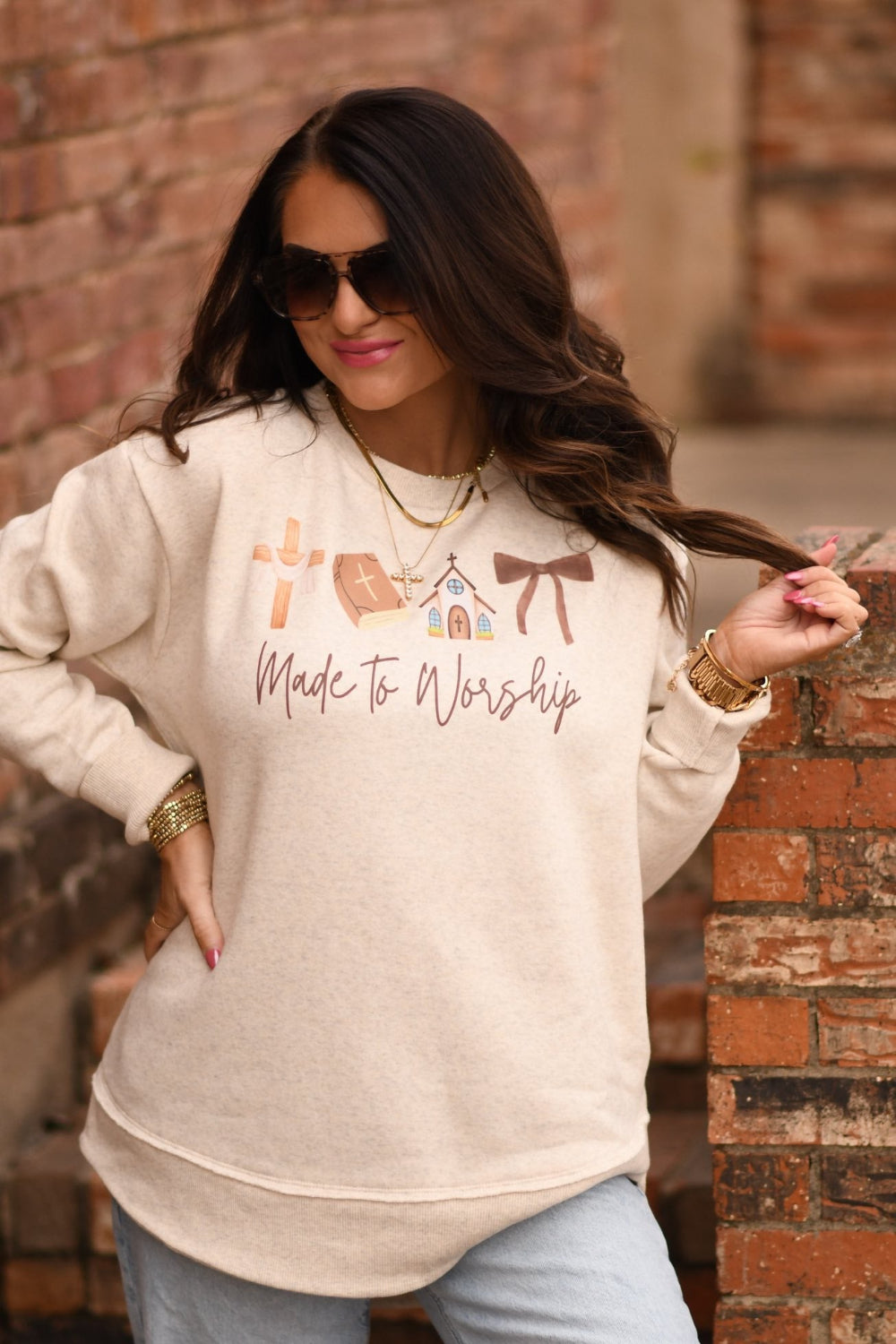 Woman wearing oatmeal Bella Canvas triblend Christian graphic tee that says Made to Worship with cross, Bible and church design styled with ripped jeans and gold jewelry
