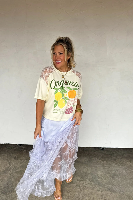 Woman wearing a graphic t-shirt with organic design and a sheer white skirt.