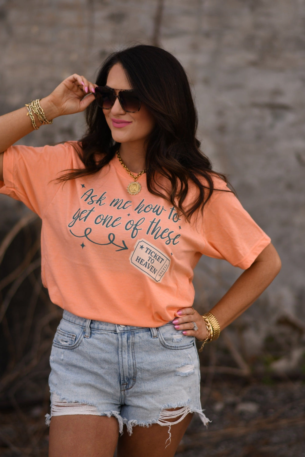 Woman wearing a heather cantaloupe Christian graphic tee that says “Ask Me How To Get One Of These” with Ticket to Heaven design, Tultex unisex fit faith shirt