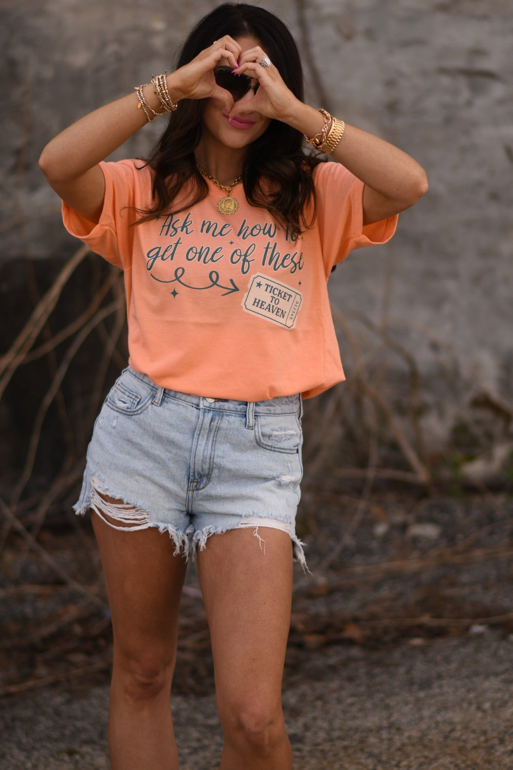 Woman wearing a heather cantaloupe Christian graphic tee that says “Ask Me How To Get One Of These” with Ticket to Heaven design, Tultex unisex fit faith shirt