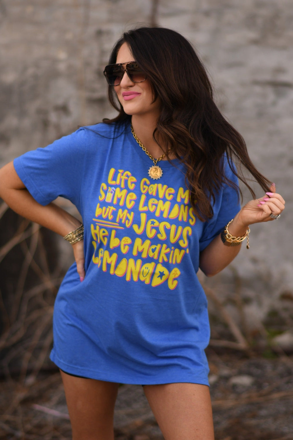 Woman wearing a Heather Royal Blue Bella Canvas unisex graphic tee that says "Life Gave Me Some Lemons but My Jesus He Be Makin' Lemonade" with yellow lemon design.