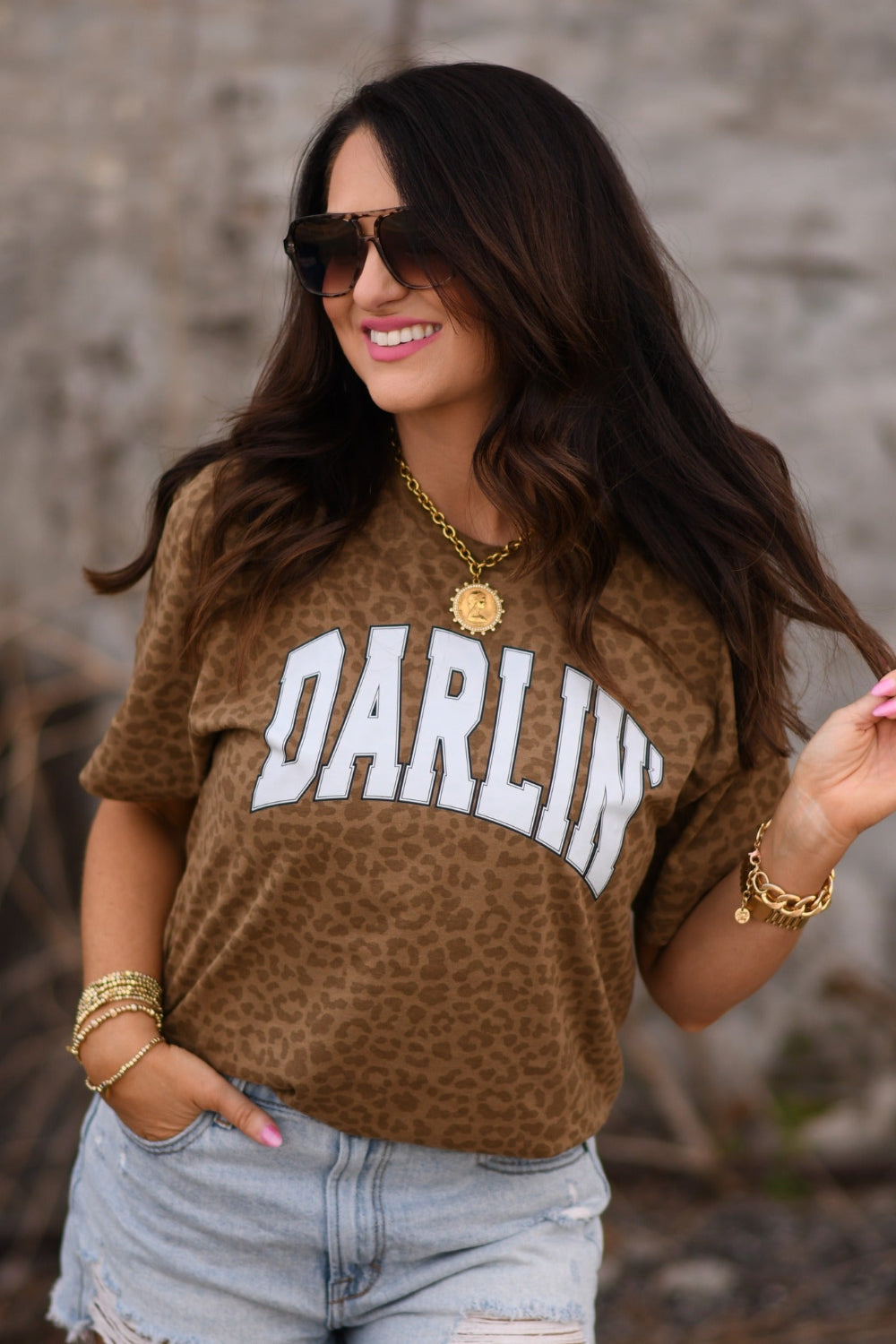 Woman wearing a brown leopard print “Darlin” graphic tee styled with denim shorts and western jewelry