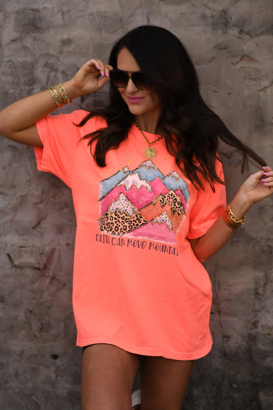 Woman wearing neon red orange Faith Can Move Mountains graphic tee with colorful mountain and leopard print design printed on Comfort Colors unisex fit shirt