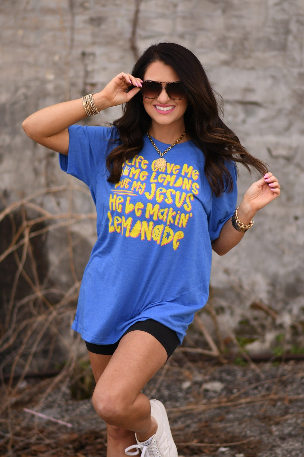 Woman wearing a Heather Royal Blue Bella Canvas unisex graphic tee that says "Life Gave Me Some Lemons but My Jesus He Be Makin' Lemonade" with yellow lemon design.