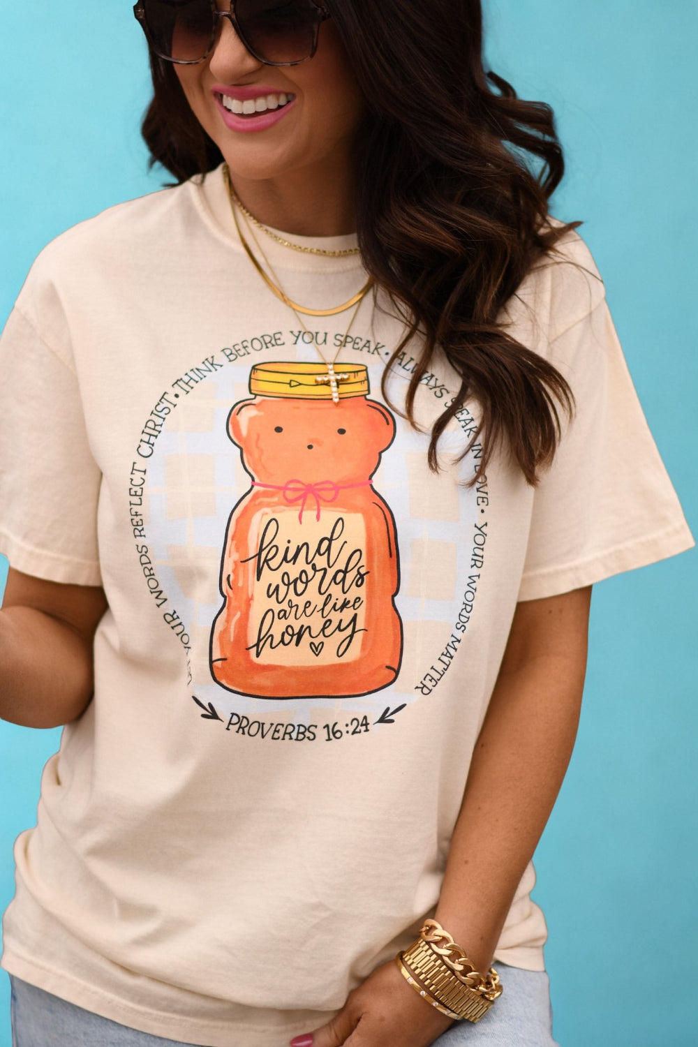 Woman wearing ivory Comfort Colors “Kind Words Are Like Honey” Christian graphic tee with honey jar design and Proverbs 16:24 scripture.