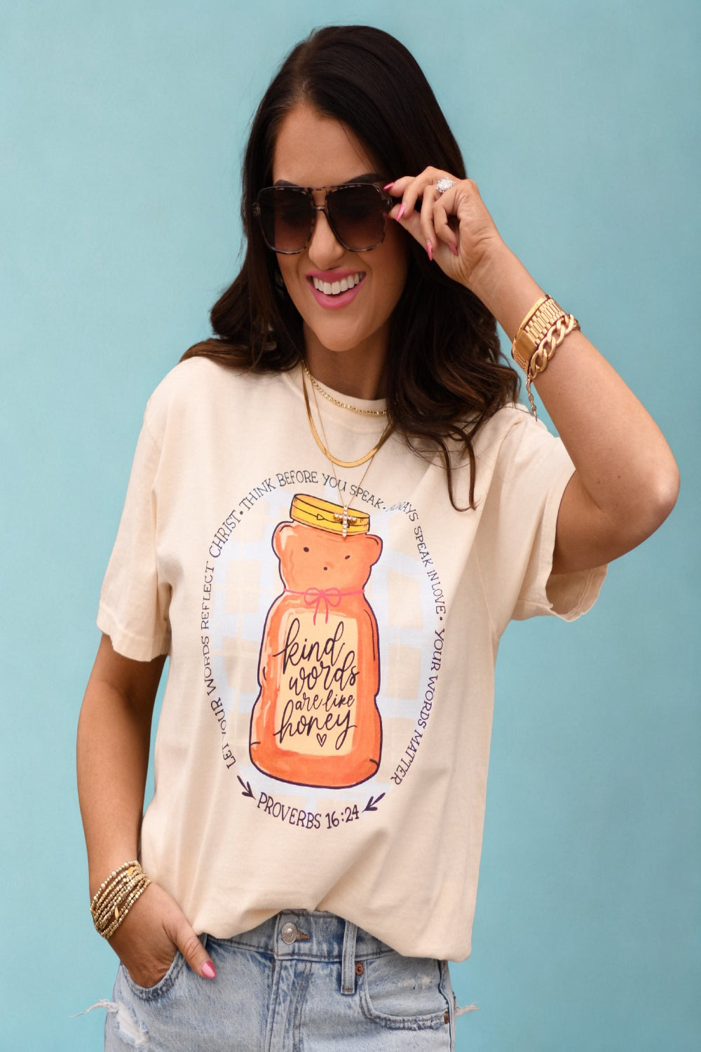 Woman wearing ivory Comfort Colors “Kind Words Are Like Honey” Christian graphic tee with honey jar design and Proverbs 16:24 scripture.