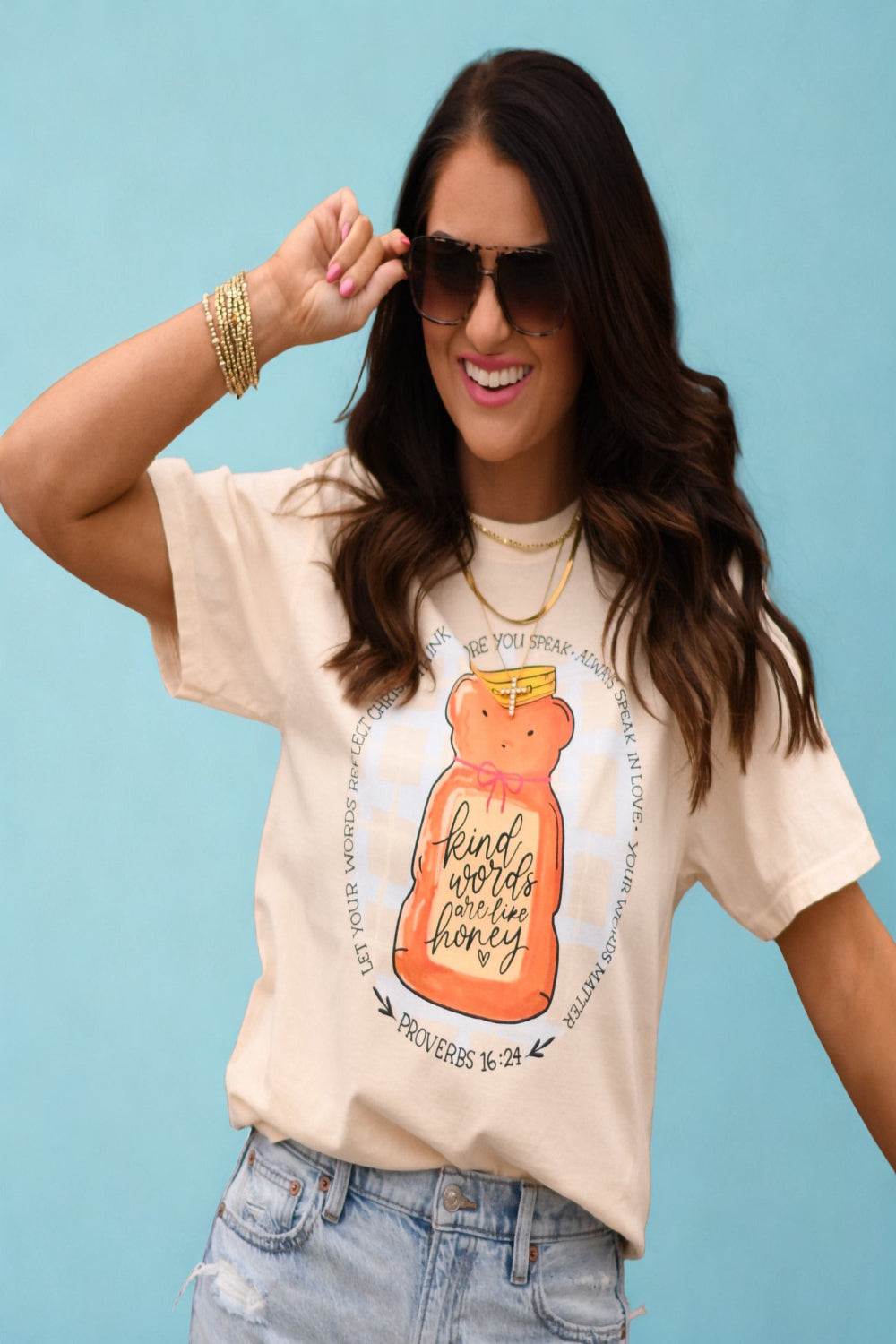 Woman wearing ivory Comfort Colors “Kind Words Are Like Honey” Christian graphic tee with honey jar design and Proverbs 16:24 scripture.