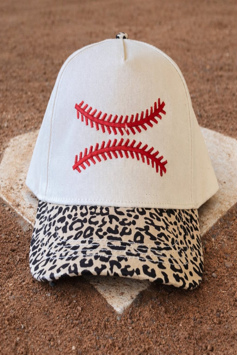 Baseball cap with red stitching and leopard print brim on a baseball field