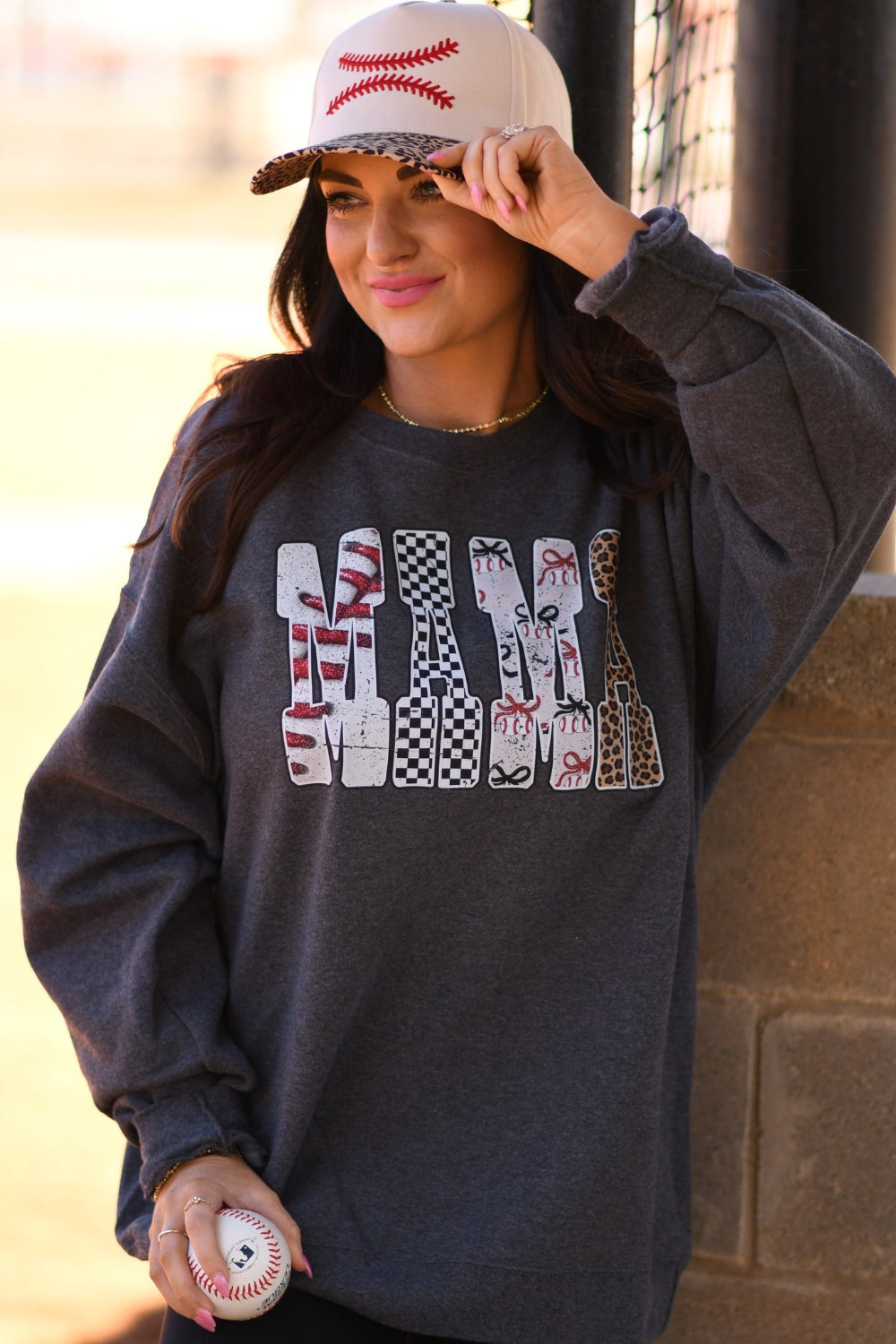 Baseball Mama heather charcoal unisex tee and sweatshirt with bold baseball print lettering, worn with embroidered baseball stitch snapback hat