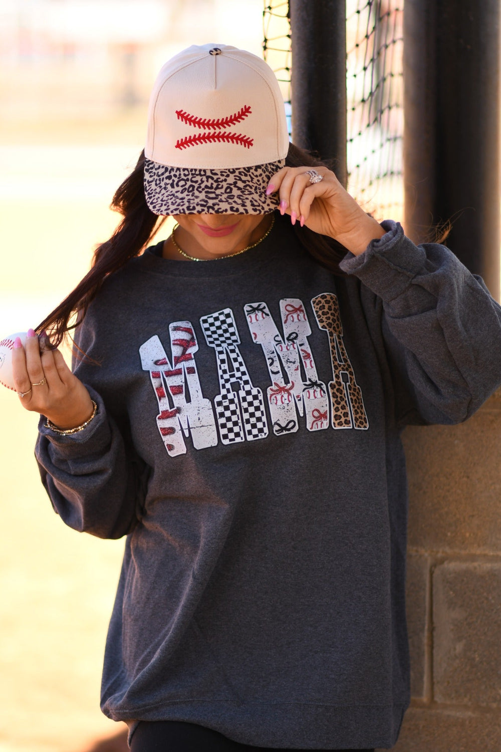 Baseball Mama heather charcoal unisex tee and sweatshirt with bold baseball print lettering, worn with embroidered baseball stitch snapback hat