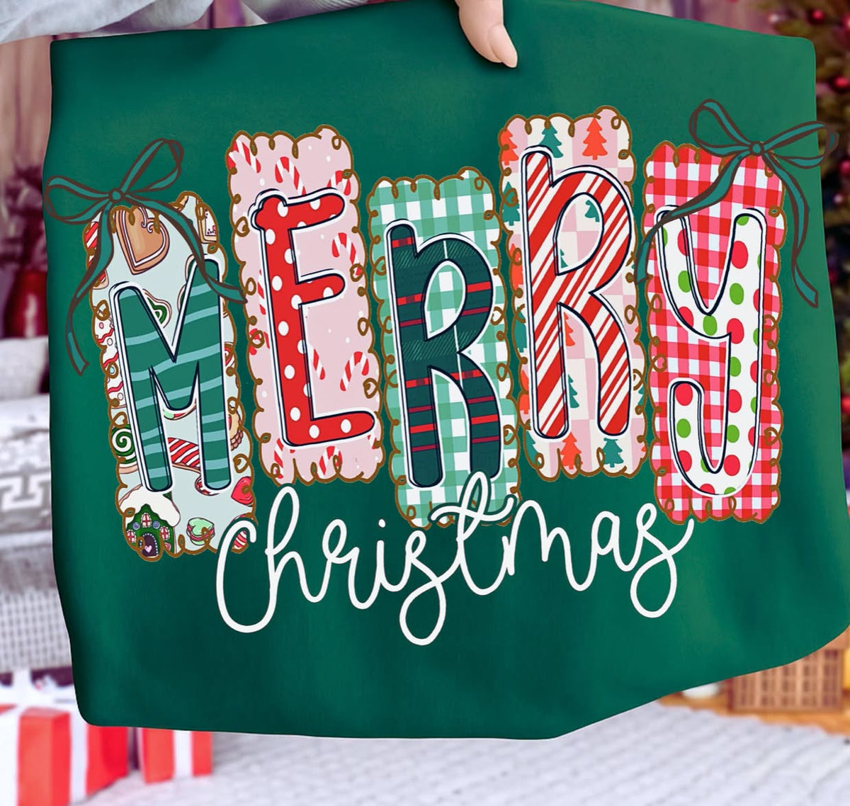 Forest Green Comfort Colors Merry Christmas graphic tee featuring colorful plaid and candy cane patterned MERRY lettering, festive bows and white Christmas script.