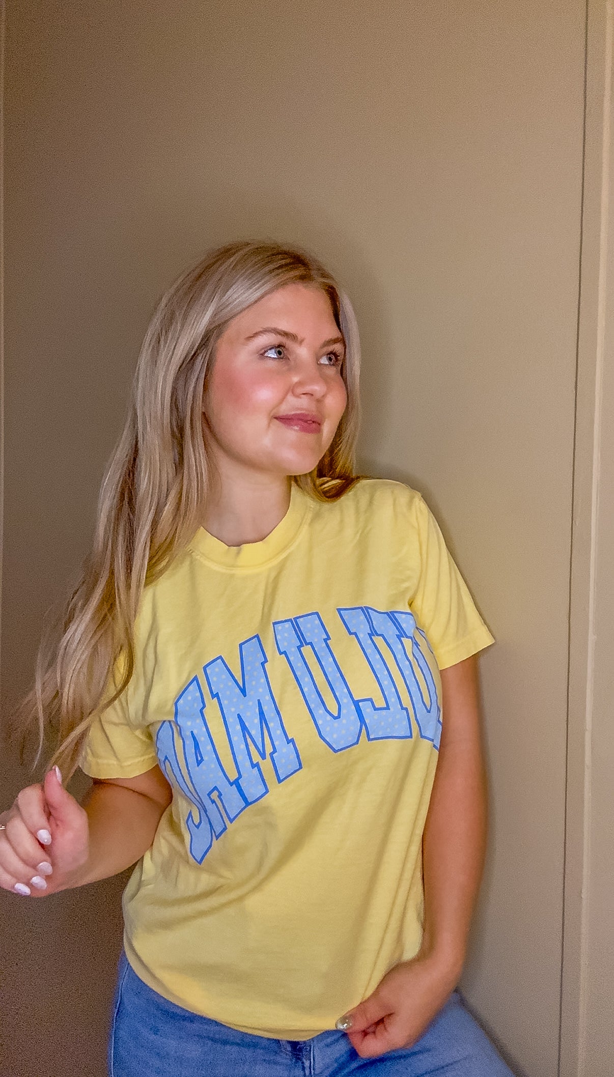 Blonde woman wearing butter yellow Comfort Colors t-shirt with blue polka dot Lulu Mac graphic, styled casually with denim