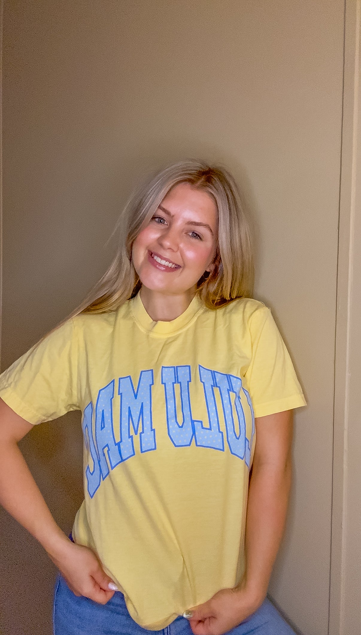 Blonde woman wearing butter yellow Comfort Colors t-shirt with blue polka dot Lulu Mac graphic, styled casually with denim