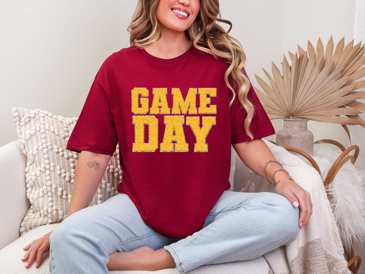 Woman wearing a red 'GAME DAY' t-shirt sitting on a couch.