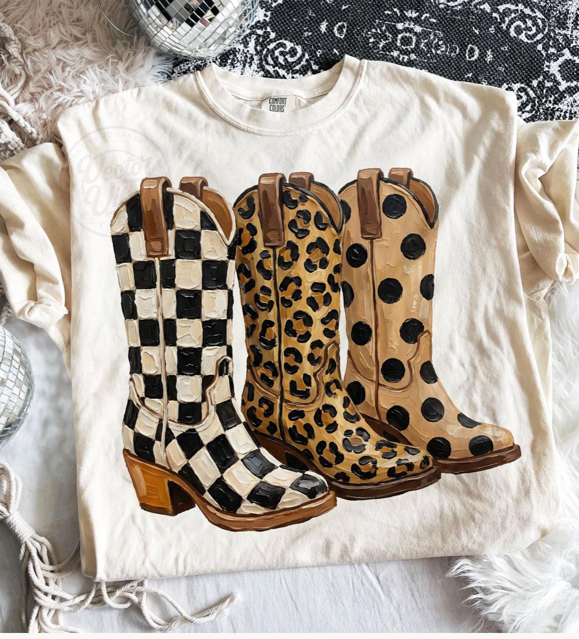 Cute sassy boots graphic tee featuring western cowgirl boots in black and white checkered, leopard print, and tan polka dot designs on a cream shirt.