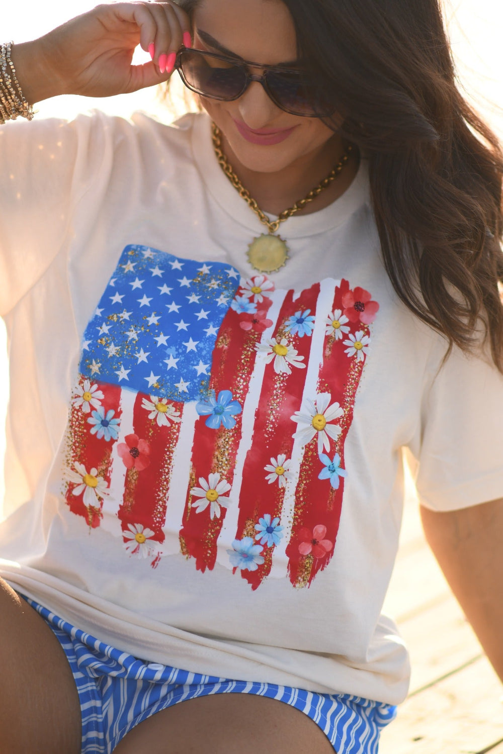 Woman wearing floral American flag graphic Bella Canvas unisex tee in natural color, patriotic floral Fourth of July shirt