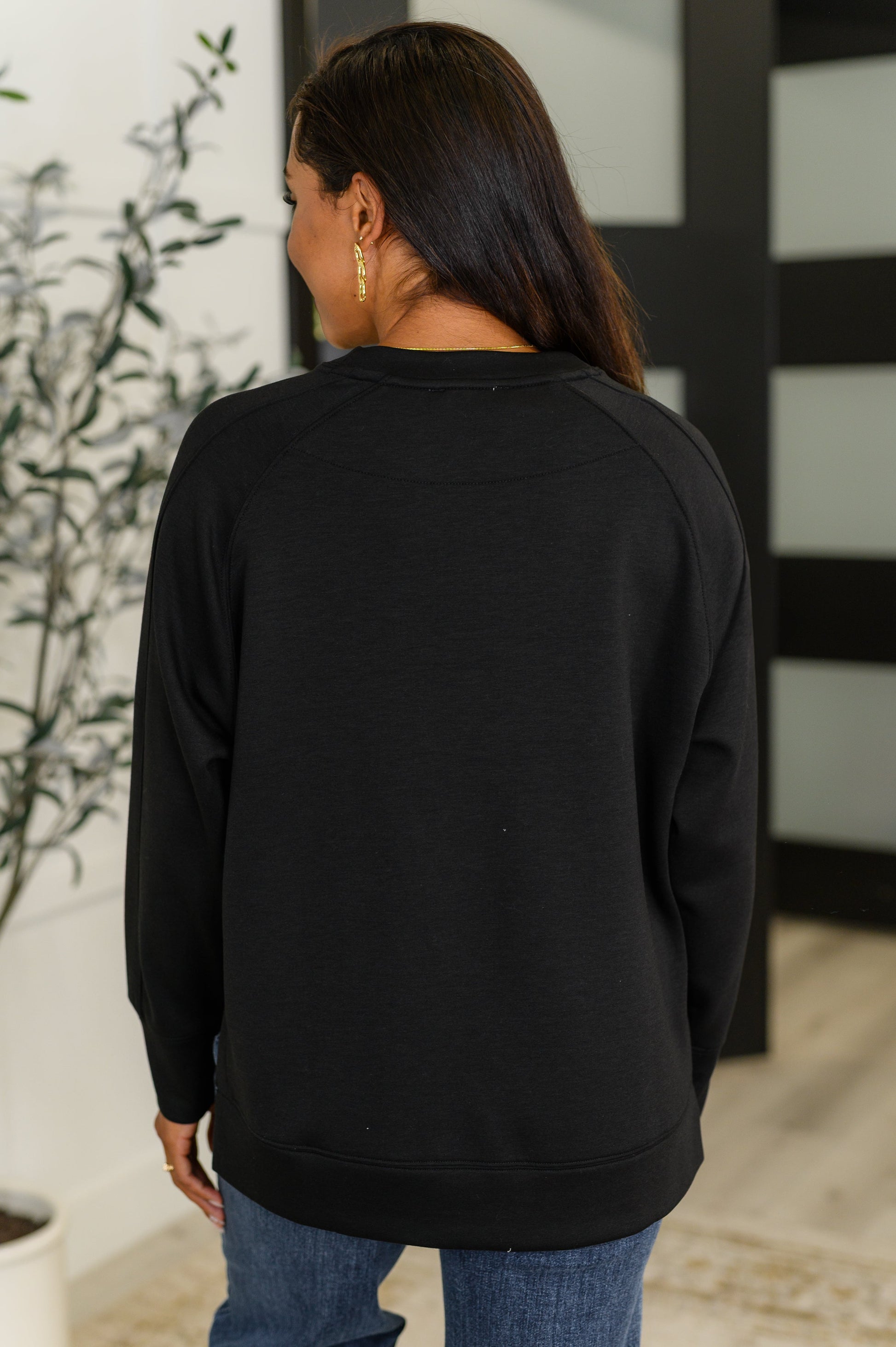 Black, relaxed scuba pullover with a round neckline, raglan sleeves, and side slits.