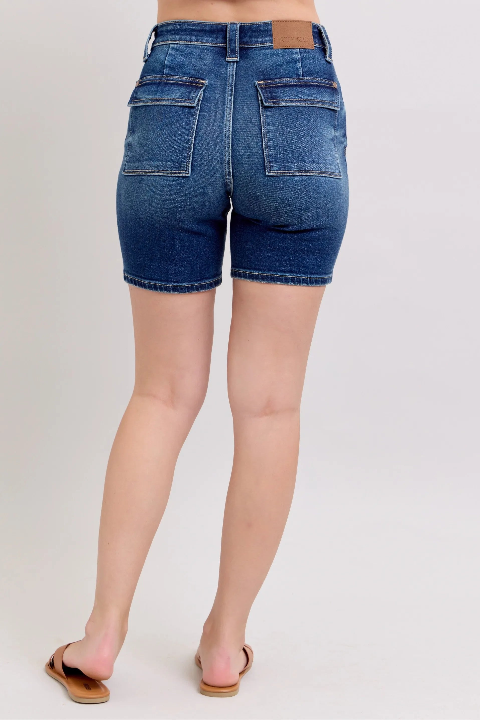 Model wearing Judy Blue high waist Bermuda denim shorts in mid-blue wash with back flap pockets and stretch fit