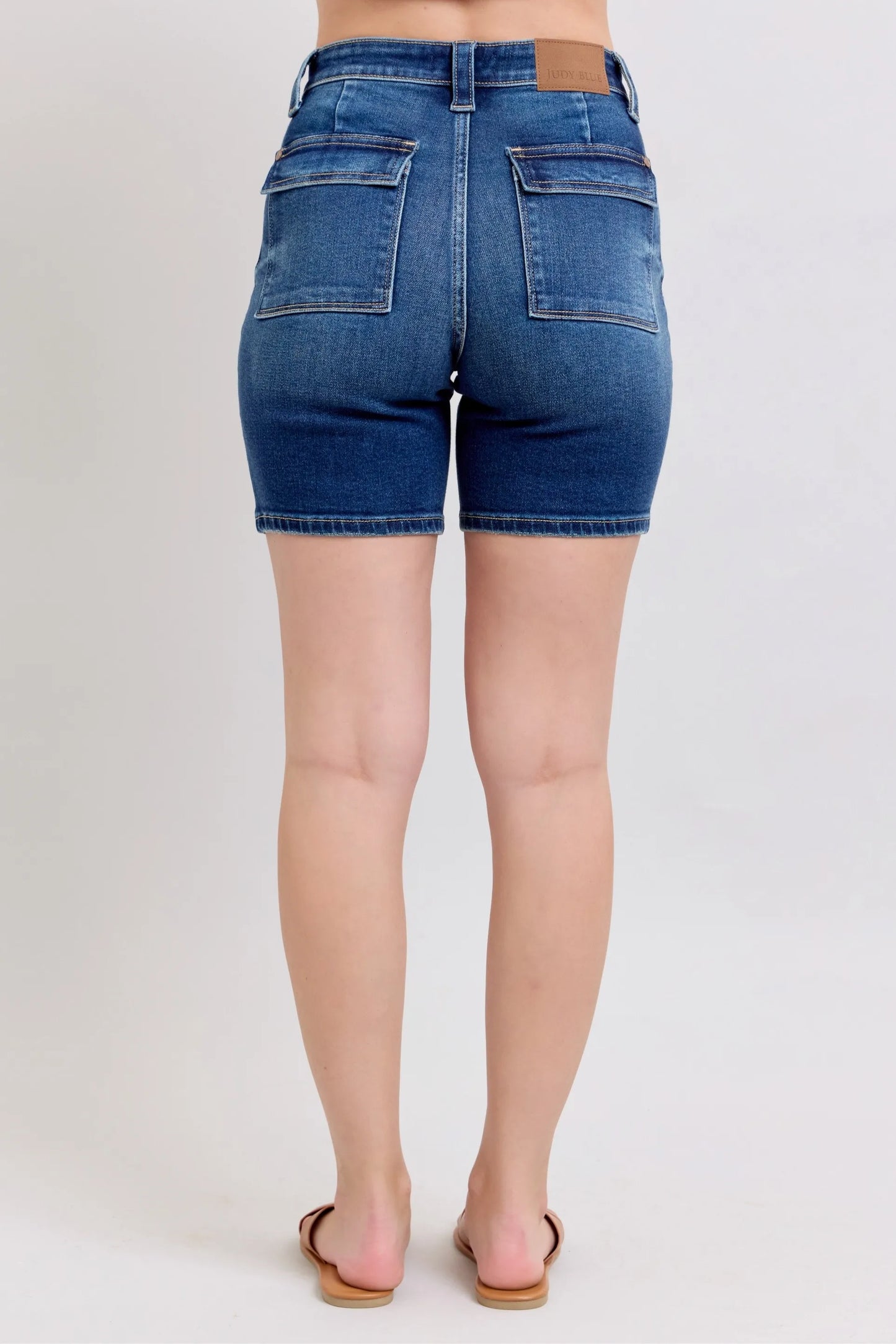 Model wearing Judy Blue high waist Bermuda denim shorts in mid-blue wash with back flap pockets and stretch fit