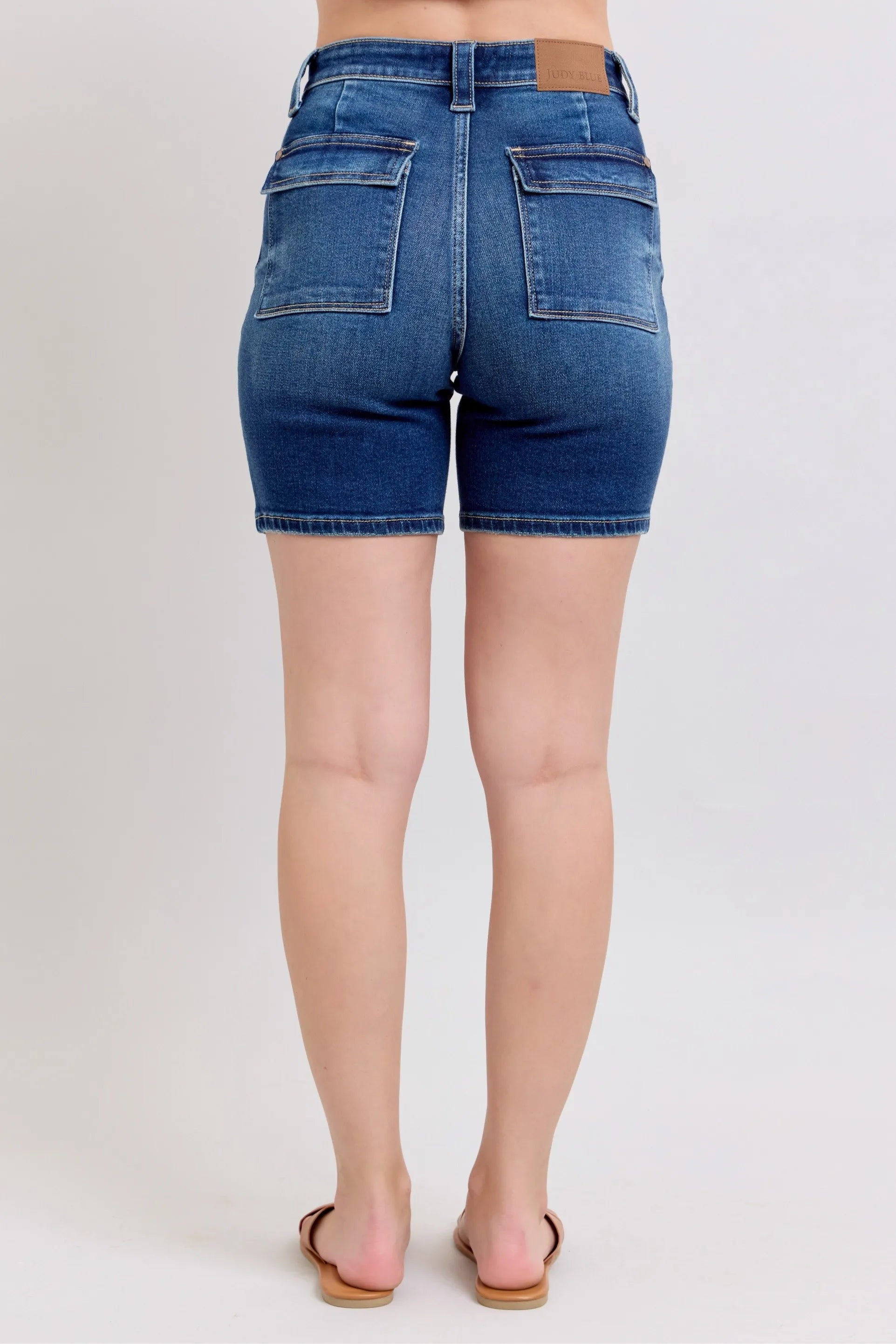 Model wearing Judy Blue high waist Bermuda denim shorts in mid-blue wash with back flap pockets and stretch fit