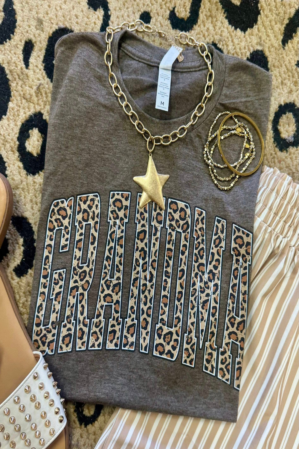 Leopard Grandma graphic tee on heather brown Tultex shirt styled with bracelets and neutral striped pants for a trendy Mother’s Day outfit.