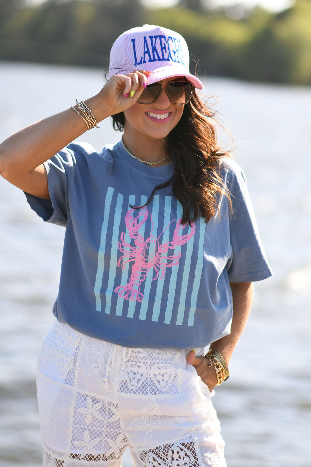 Woman wearing ice blue lobster stripes graphic tee styled with sunglasses outdoors