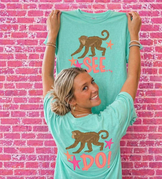 Woman modeling Island Reef Comfort Colors Monkey See Monkey Do graphic t-shirt set with front and back design against pink brick wall