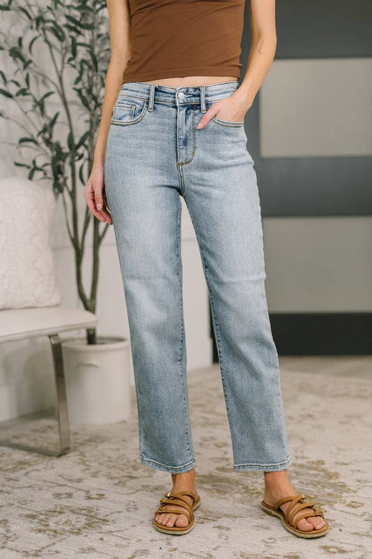 Model wearing Judy Blue high-rise straight leg light wash jeans with lightly distressed hem and zipper fly