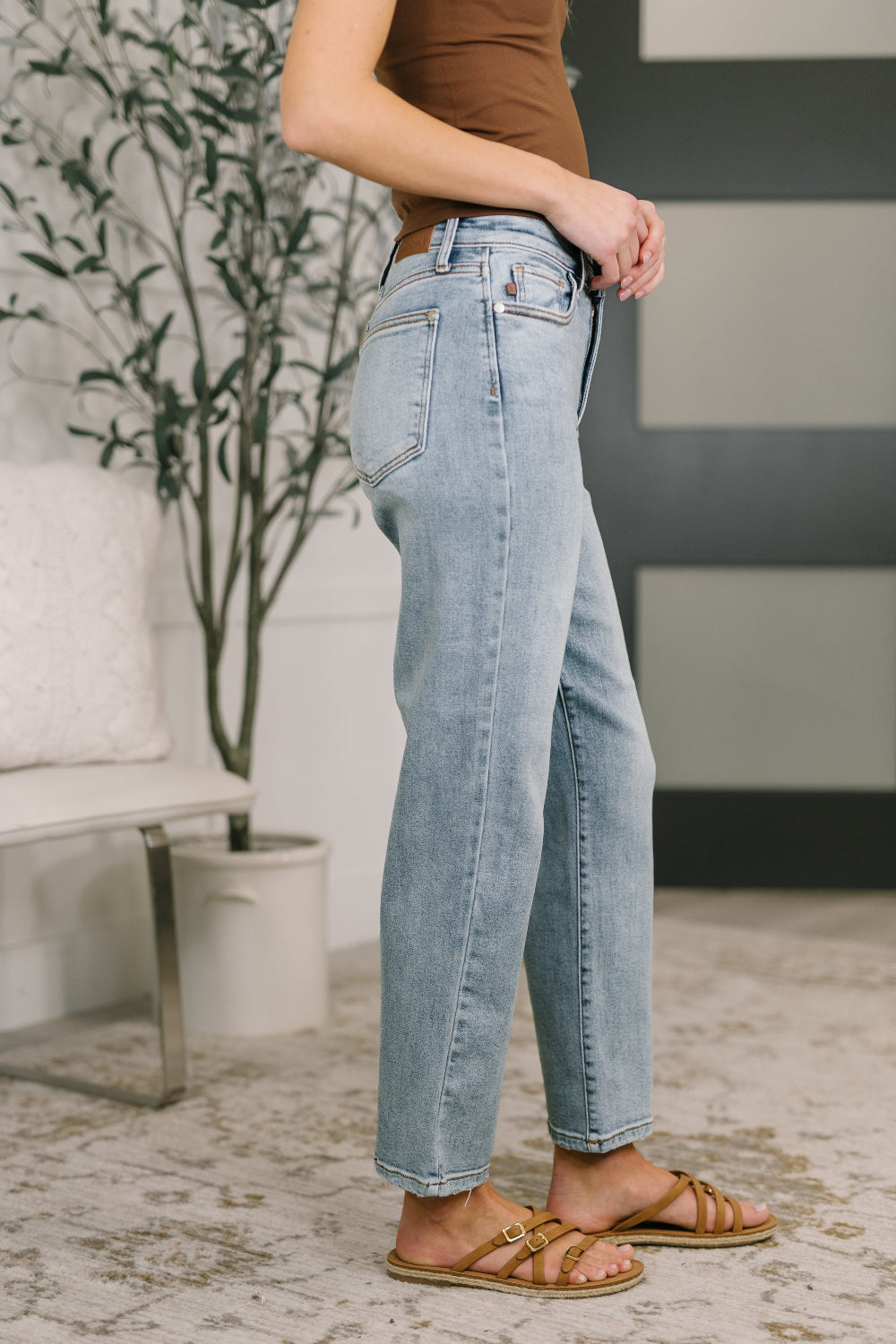 Model wearing Judy Blue high-rise straight leg light wash jeans with lightly distressed hem and zipper fly