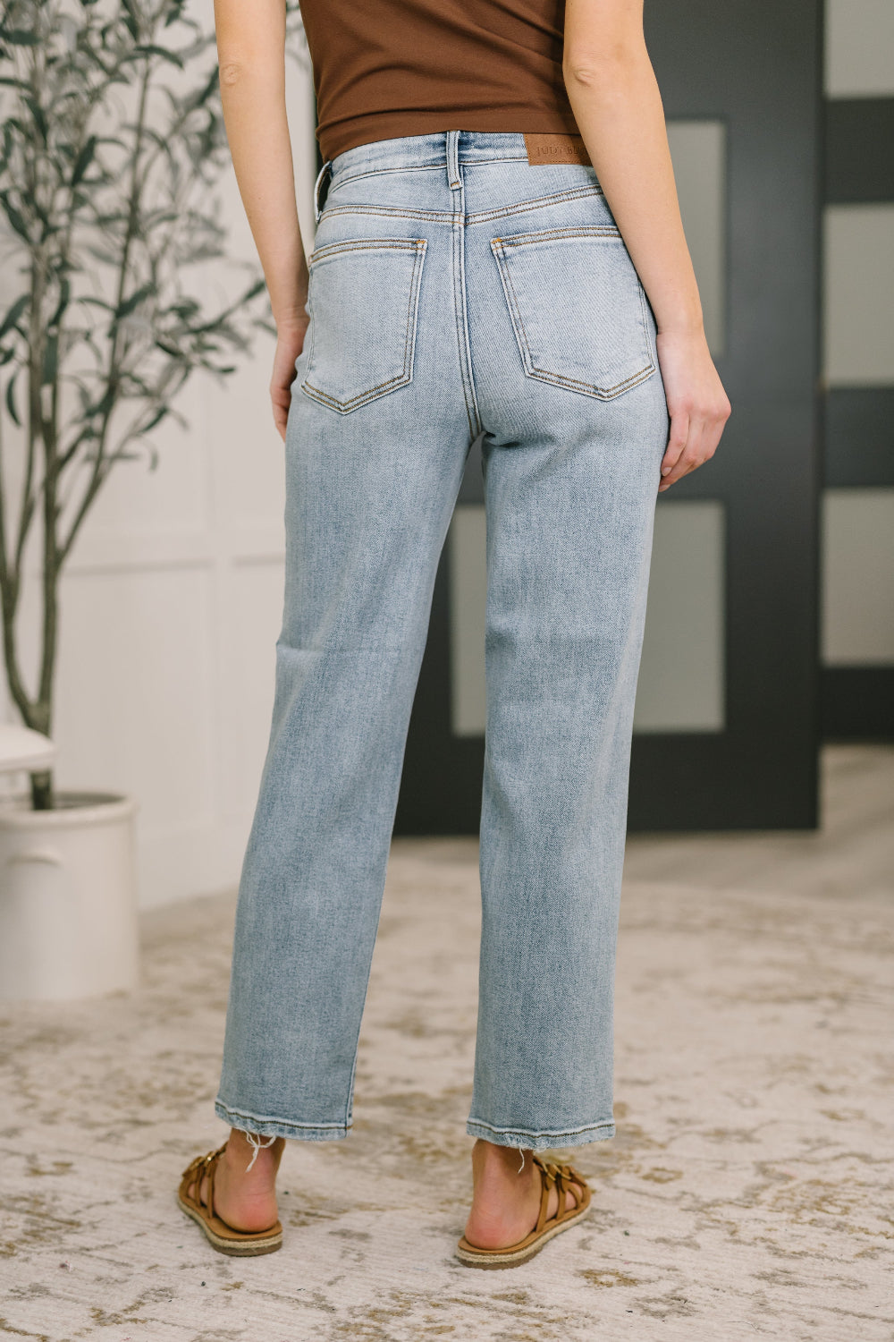 Model wearing Judy Blue high-rise straight leg light wash jeans with lightly distressed hem and zipper fly