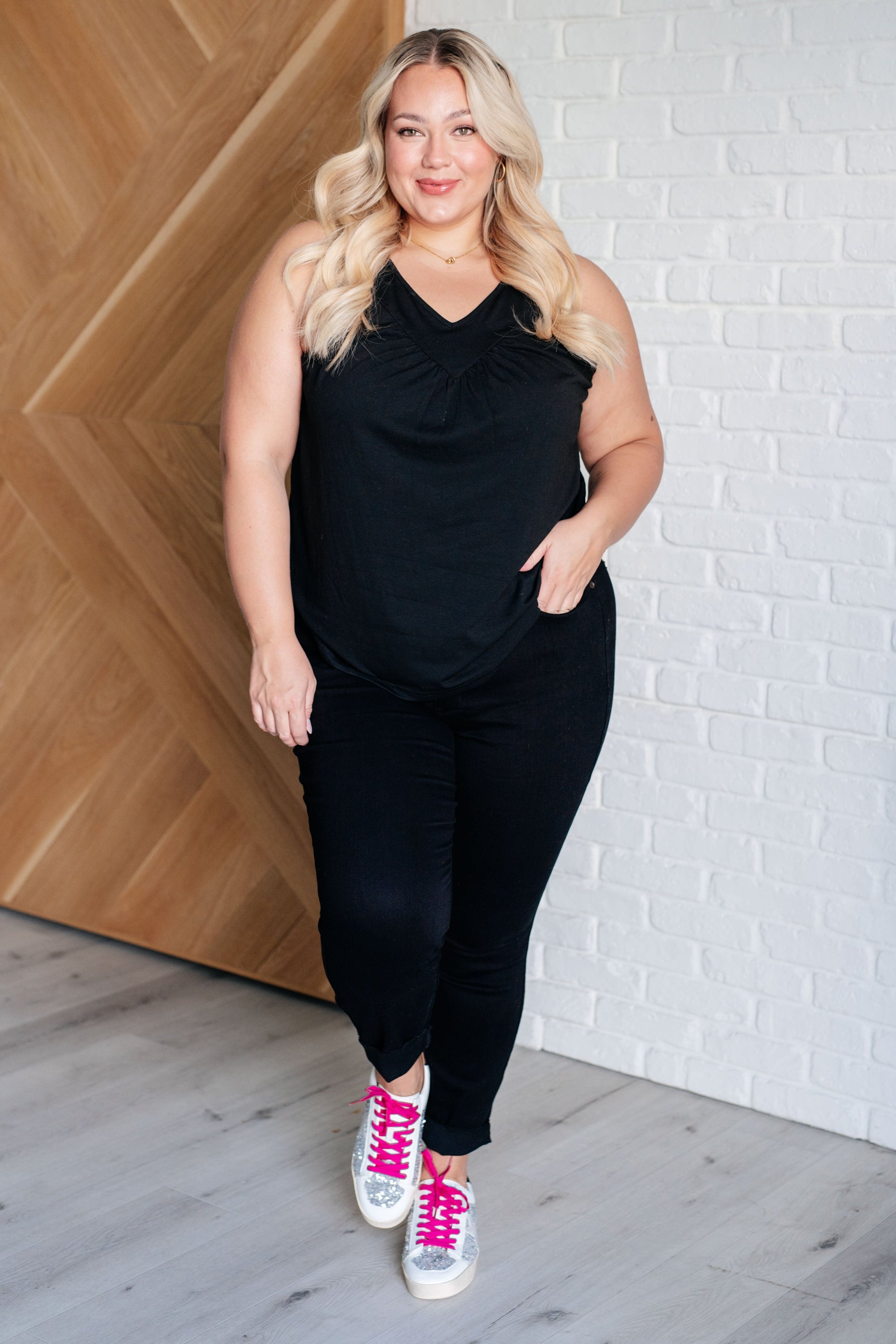  black V-neck tank top with ruched detailing, sleeveless design, in a casual setting.