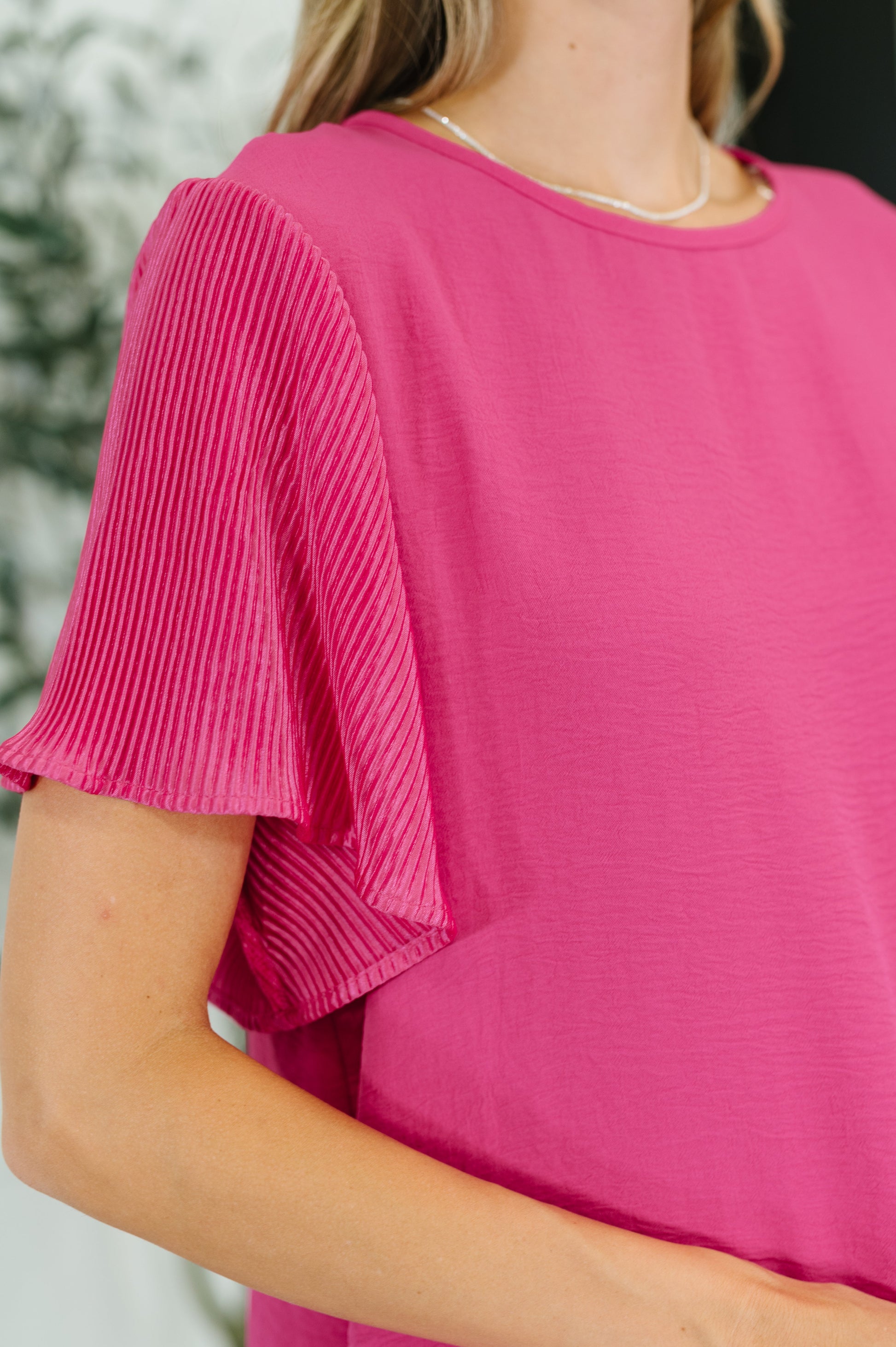 Pink ruffle sleeve top with a round neckline and short, pleated sleeves.
