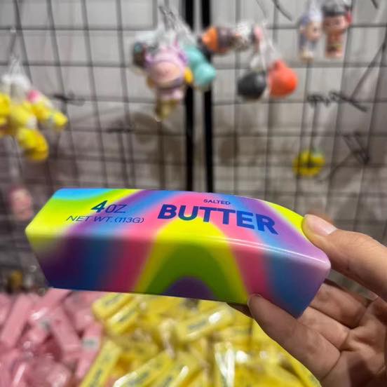 Rainbow butter squishy held in hand with vibrant gradient colors and soft slow rising texture