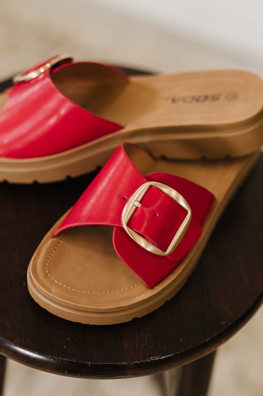 Red slide sandals with a gold buckle by SODA