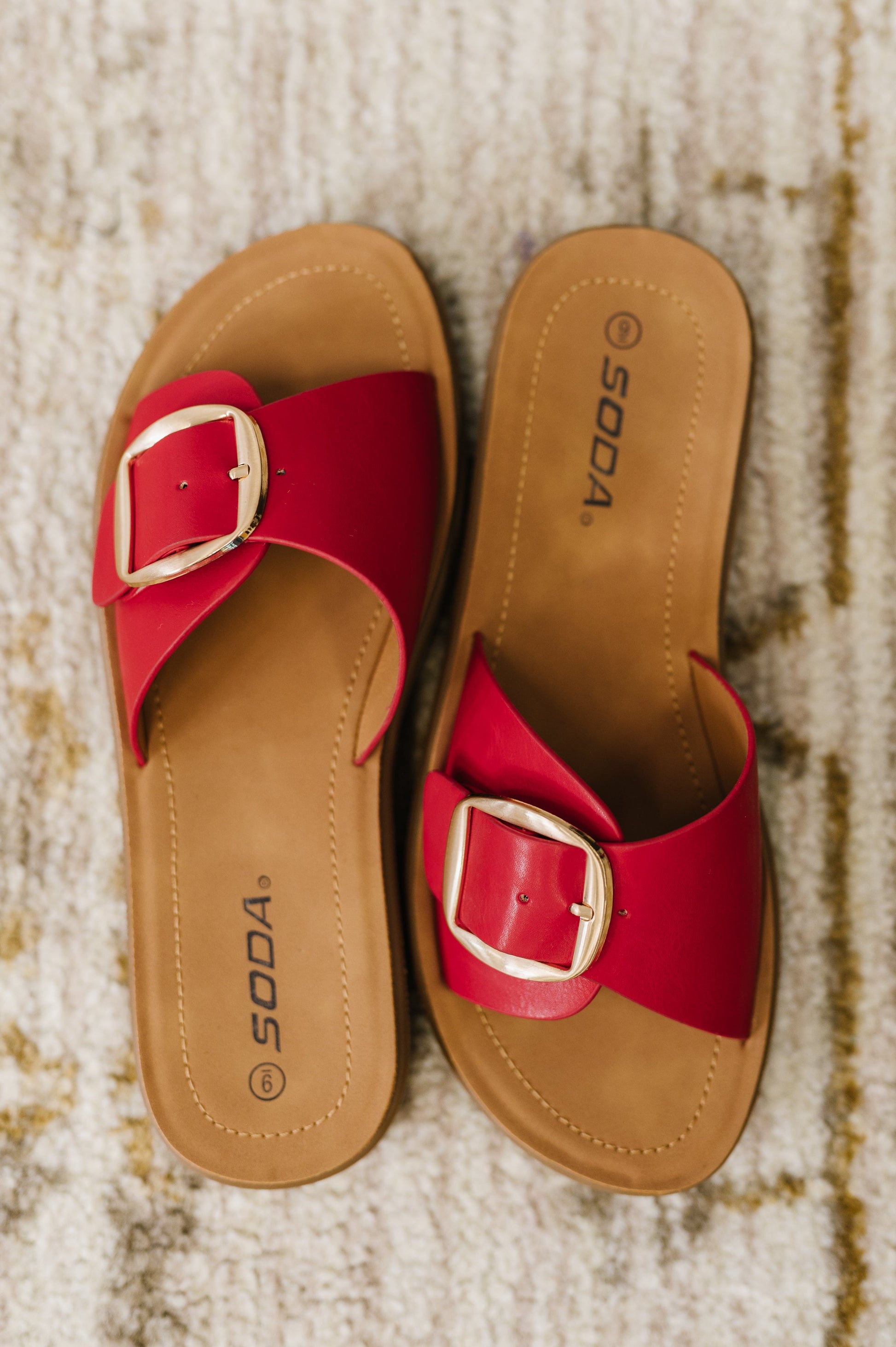 Red slide sandals with a gold buckle by SODA