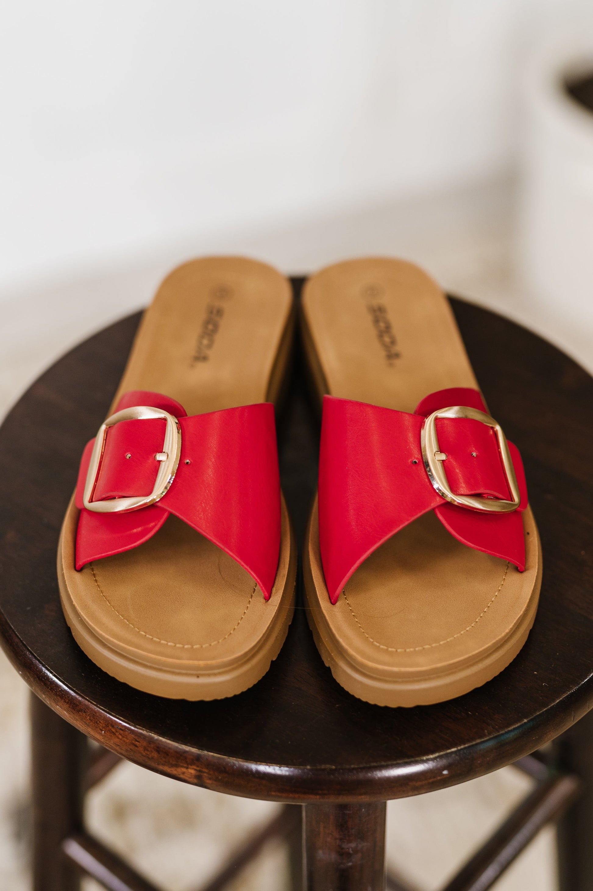 Red slide sandals with a gold buckle by SODA