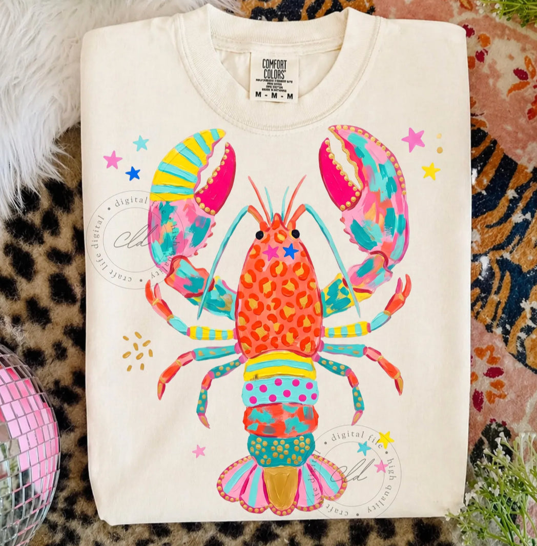 White graphic t-shirt with a bright colorful lobster design featuring pink, teal, orange, yellow, leopard print, and star accents.