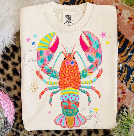 White graphic t-shirt with a bright colorful lobster design featuring pink, teal, orange, yellow, leopard print, and star accents.