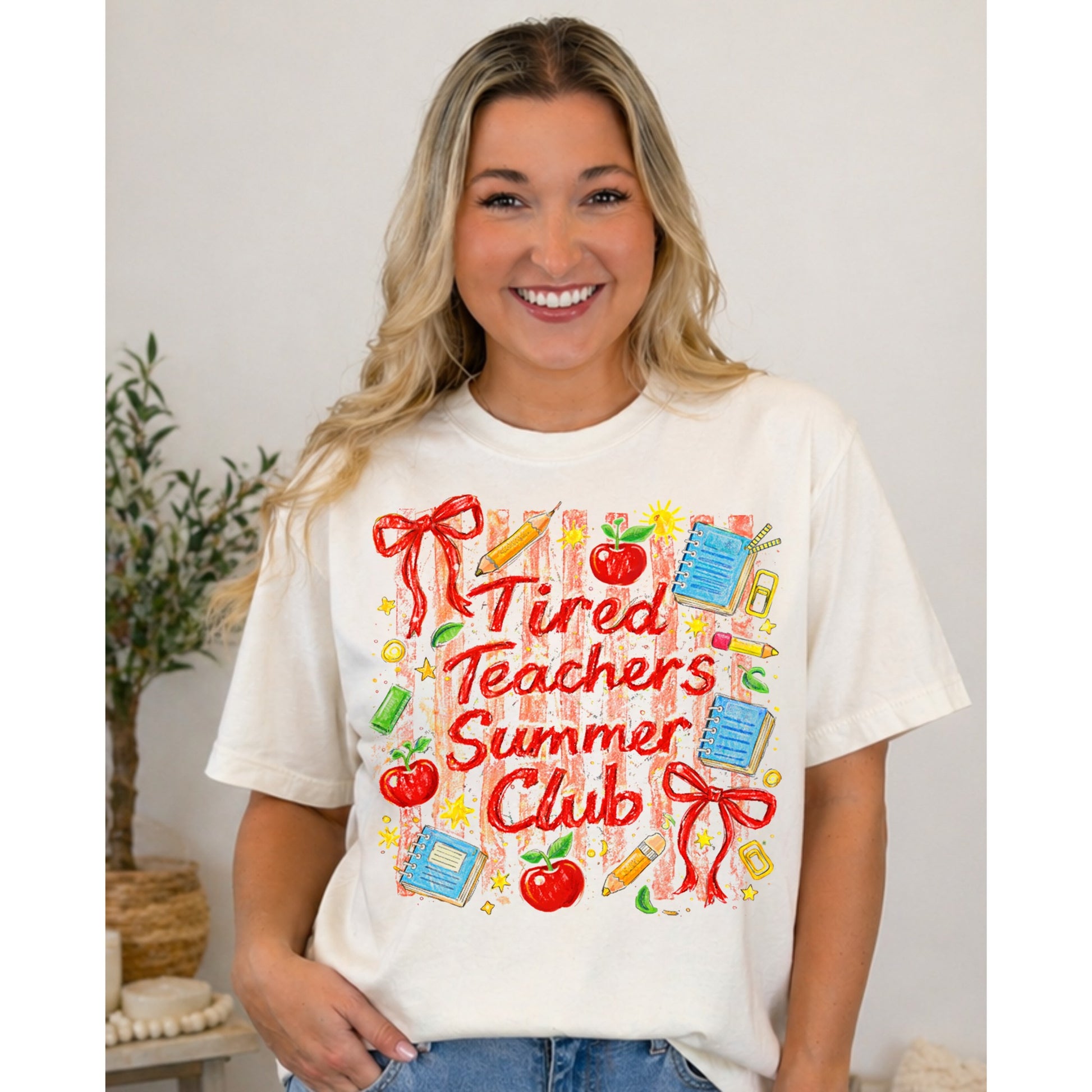Ivory teacher graphic tee with “Tired Teachers Summer Club” design featuring apples, notebooks, and school icons